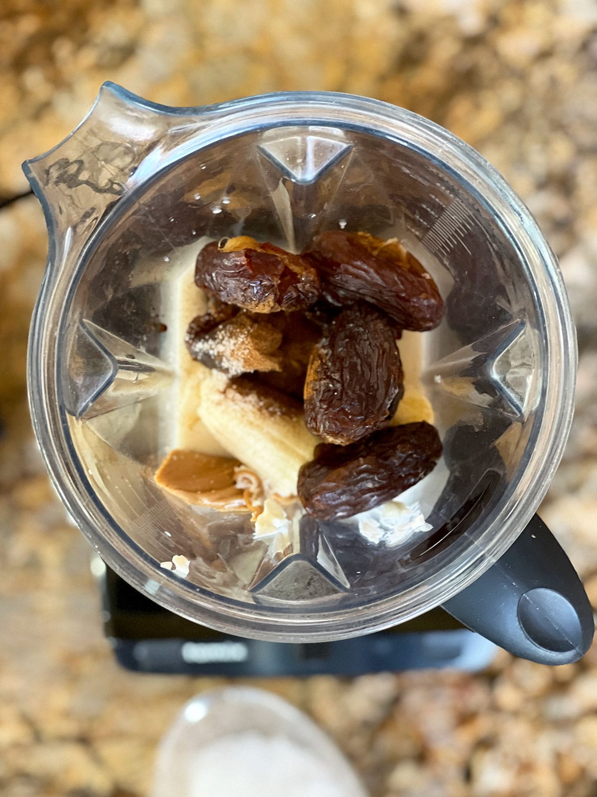 Top down view of blender with dates and bananas showing.