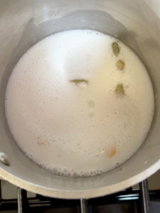 Coconut cream and cardamom pods and orange in a pot.