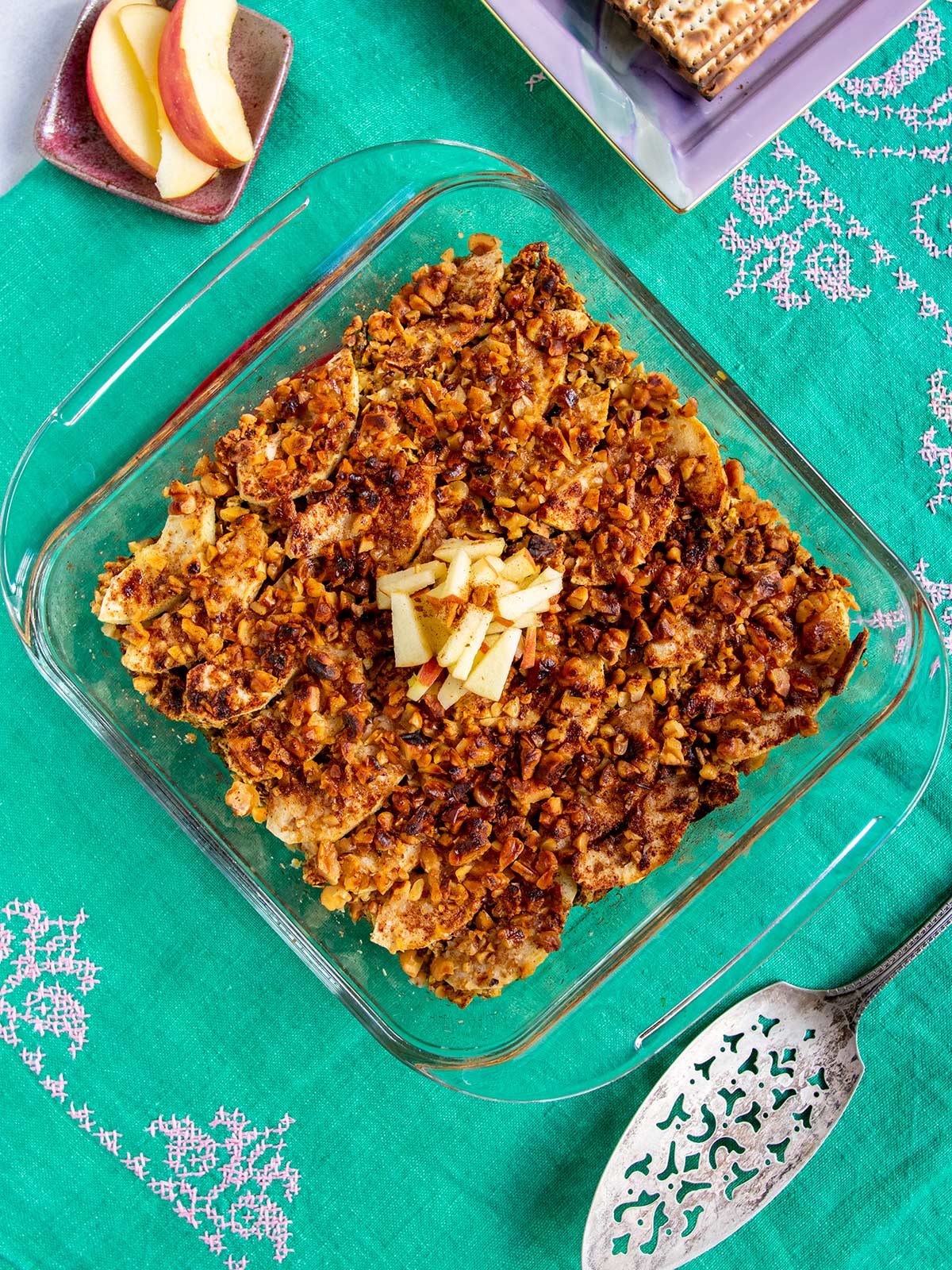 Whole pan of kugel on turquoise tablecloth with serving tool.