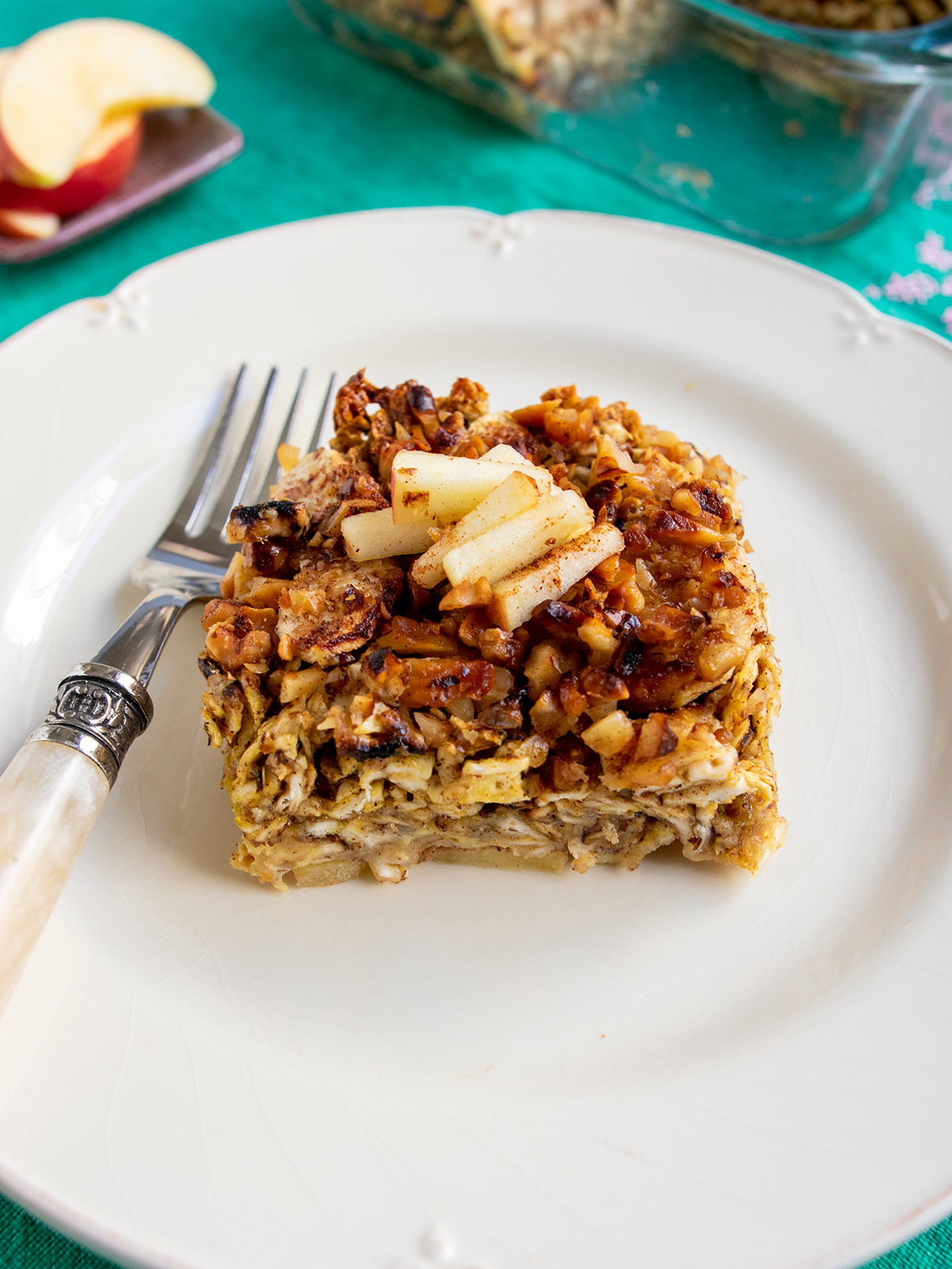 Matzo farfel kugel on a white plate with a fork and matzo in the background.
