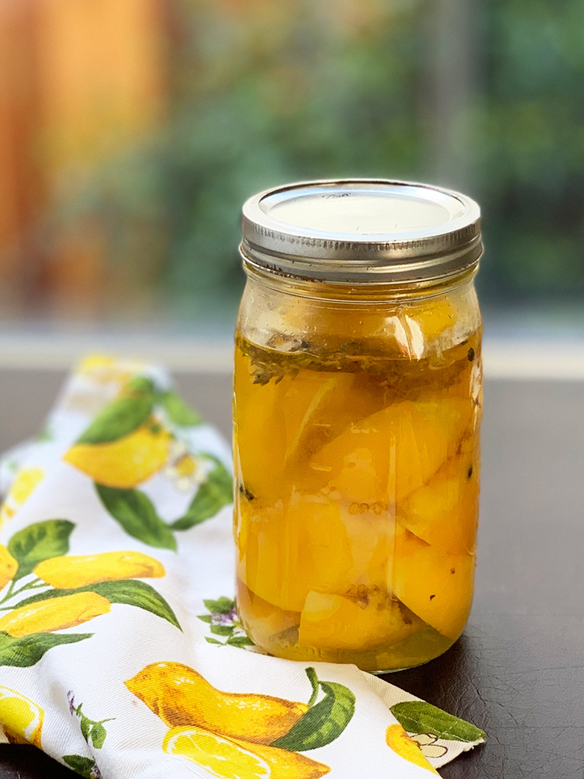 Preserved lemons ready to eat in a jar with a lemon napkin next to it.