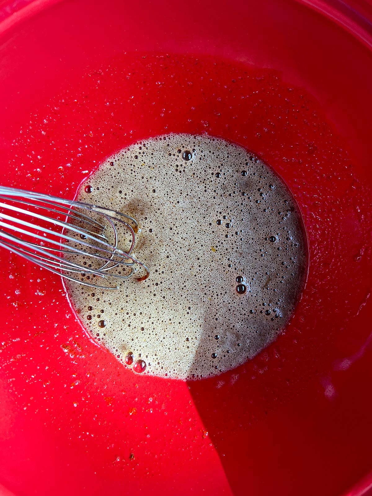 Wet ingredients and whisk in red bowl.