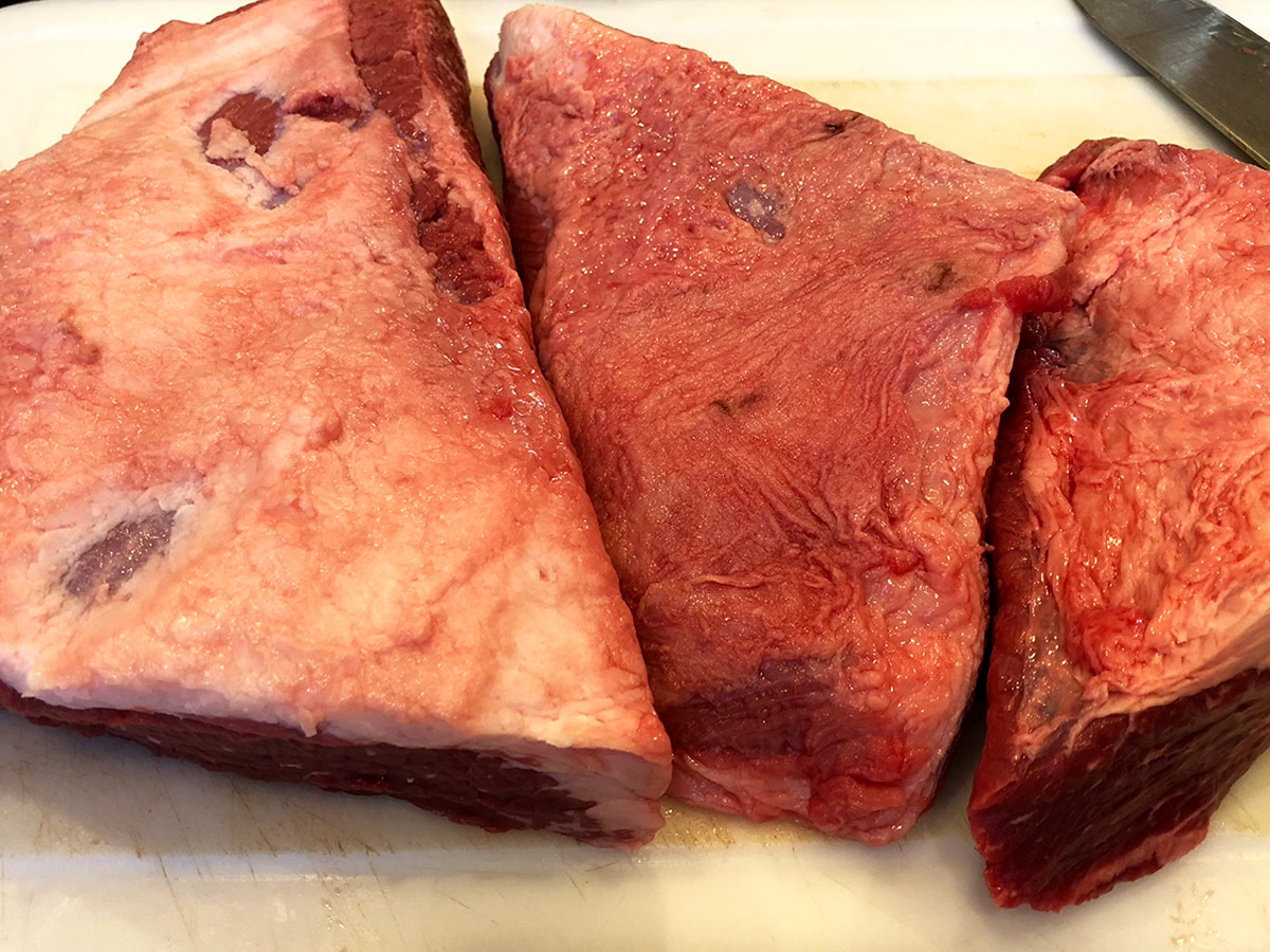 Three pieces of brisket with the fat side showing.