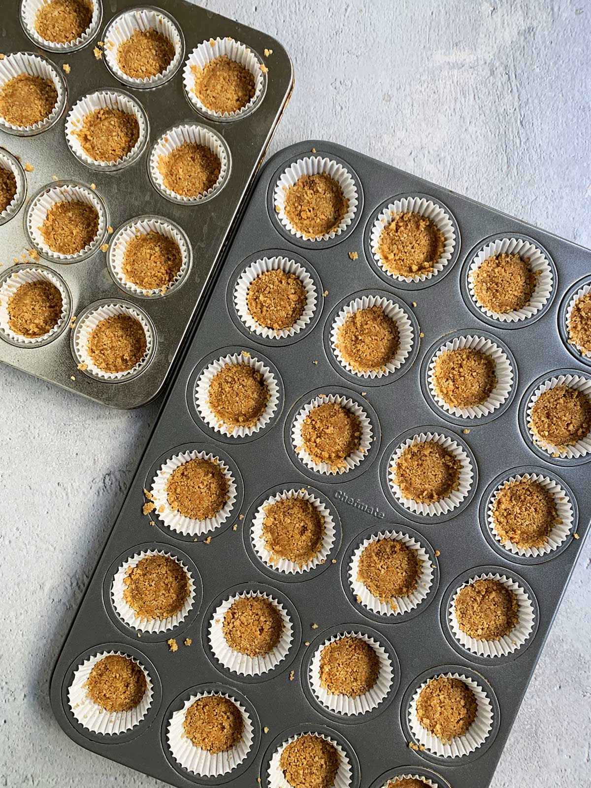 Two pans of mini cheesecakes bites waiting for the crust to be baked.