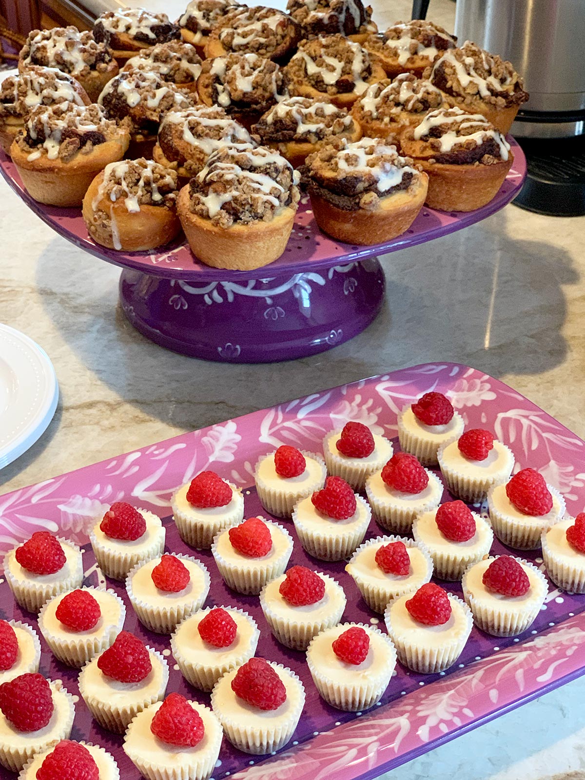 Mini cheesecakes on a purple platter with mini babkas in the background.