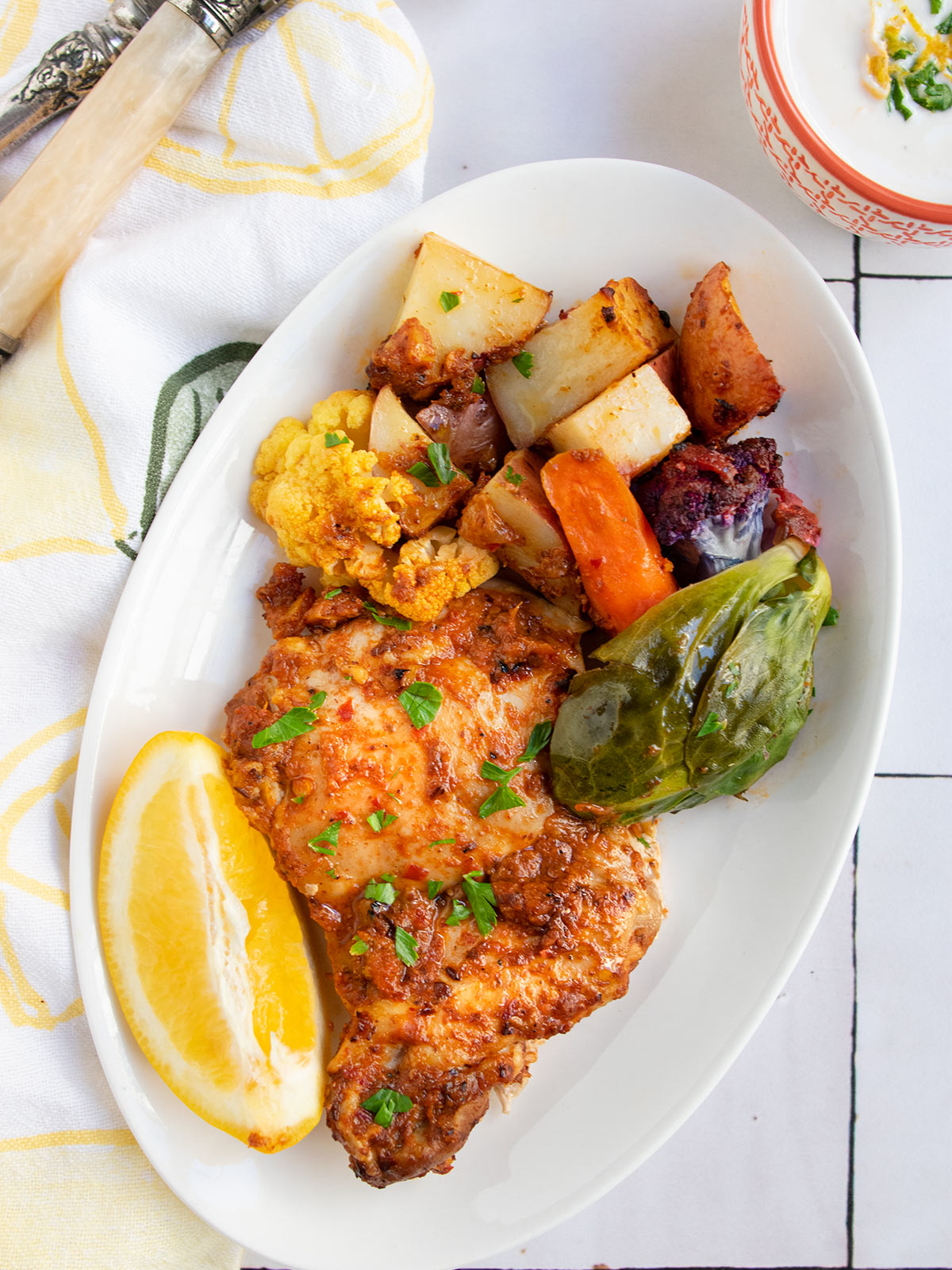 As part of Rosh hashanah food ideas post, a white plate showing harissa chicken and vegetables to introduce the chicken section of the post.