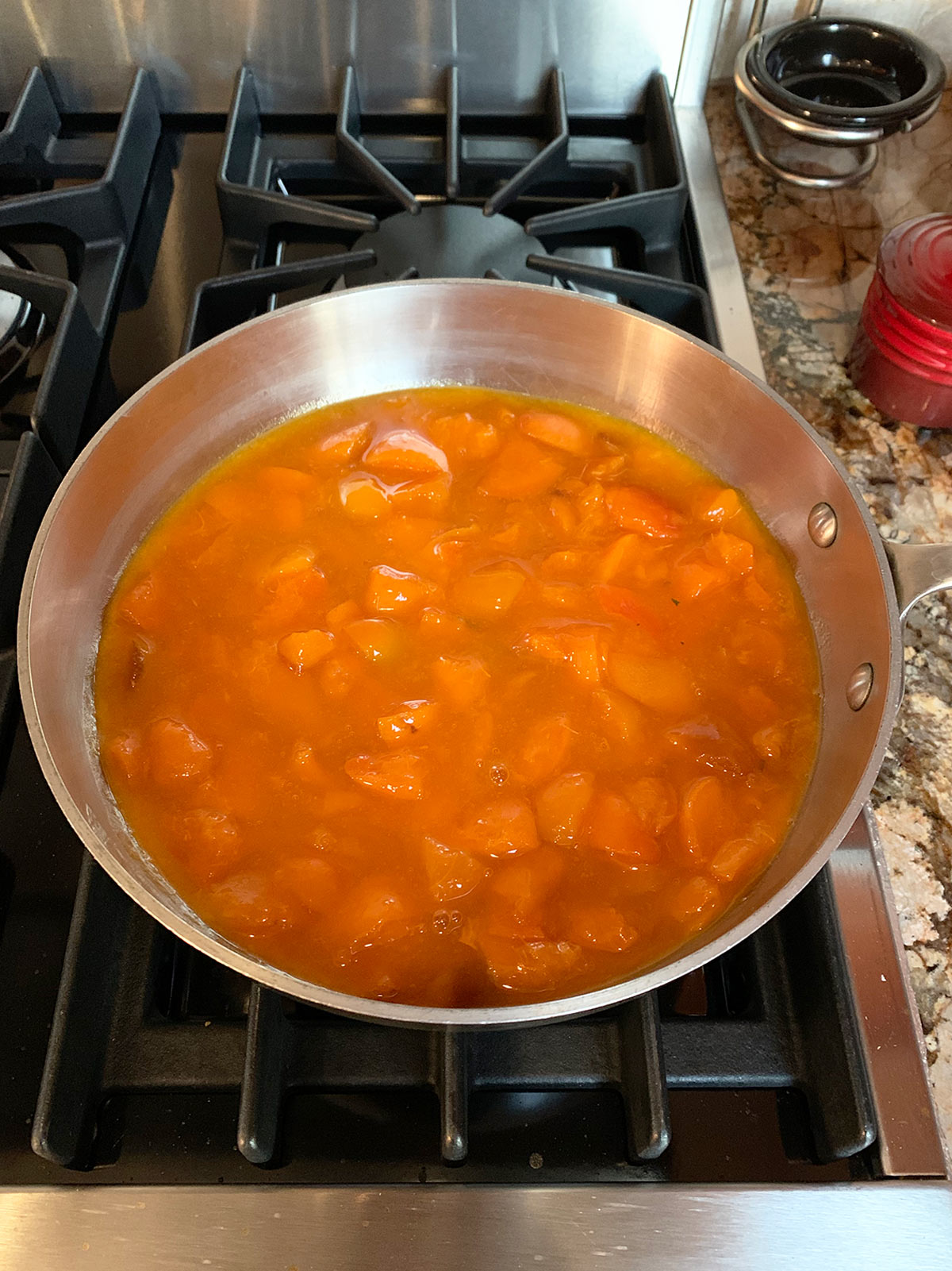 Saucepan with macerated apricot preserves starting the boiling process.