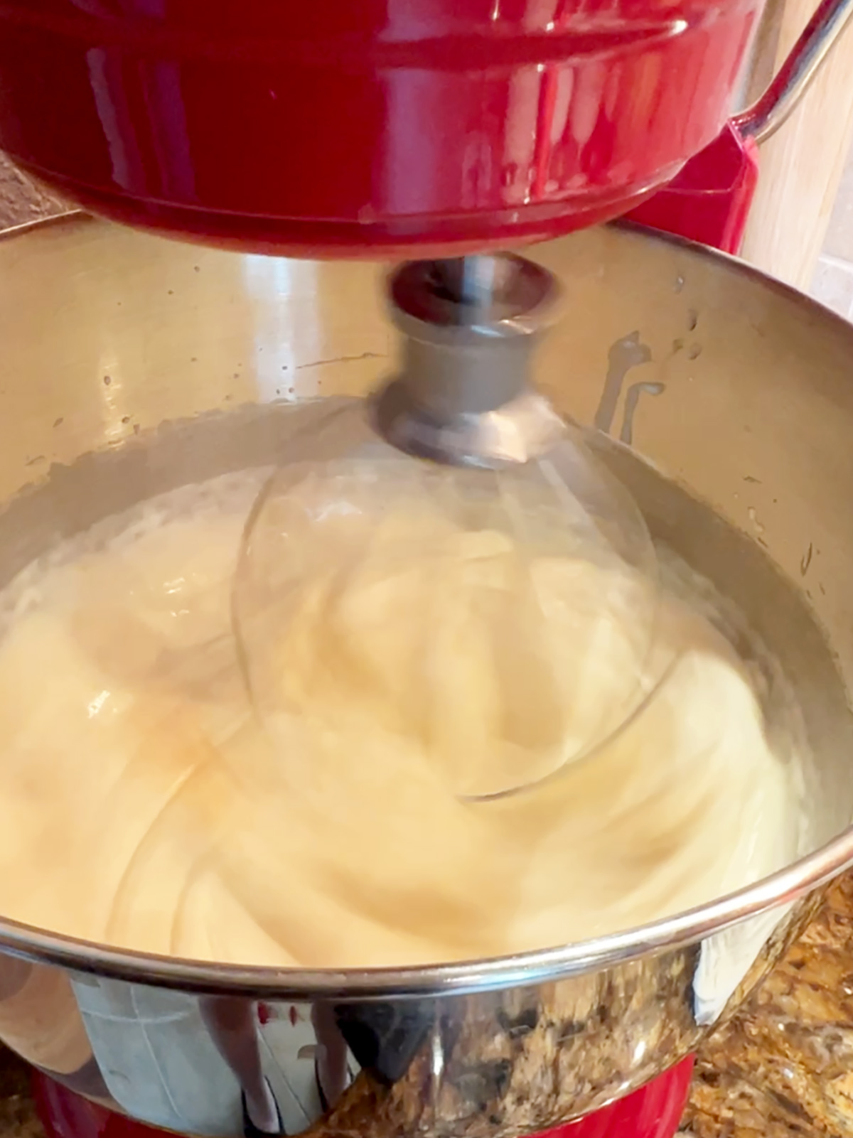Ice cream base in mixer with whisk in motion showing tracks in mixture.
