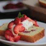 Roasted strawberry shortcake on white plate with fresh strawberries and whipped cream.