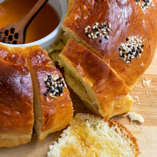 Close up of round challah with honey in the center and a piece with honey on top.