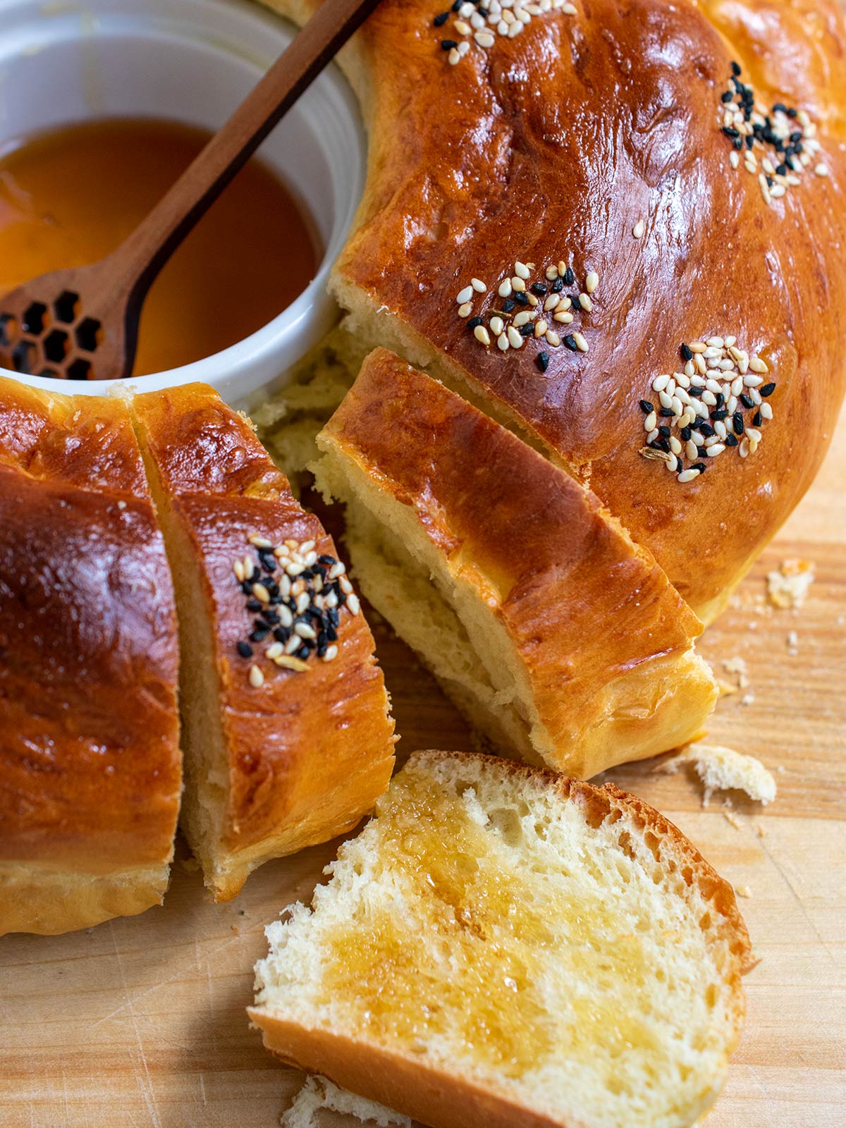 Close up of round challah with honey in the center and a slice with honey on top.