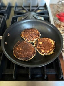 Three cottage cheese pancakes flipped over in a small fry pan.