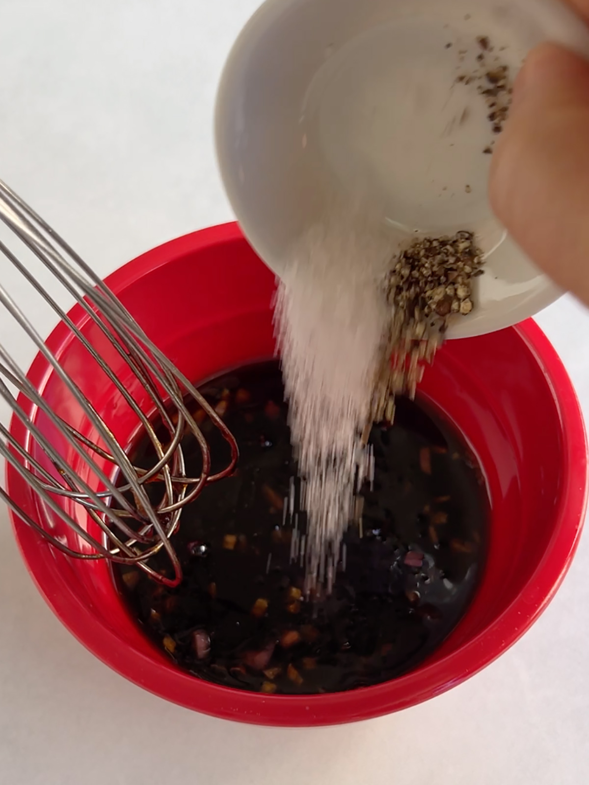Close up of salt and pepper getting whisked into the pomegranate molasses dressing.