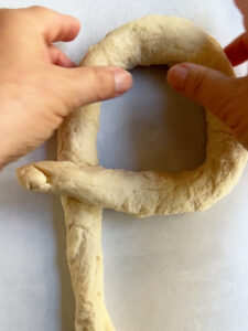 Step 1 of making a single strand challah braid showing the key formation.