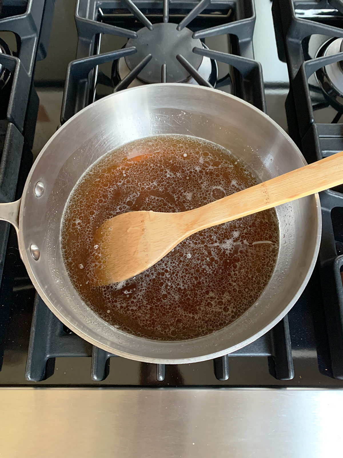 Wooden spoon in pot and honey and sugar have dissolved.
