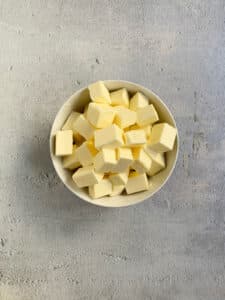 Butter cut into cubes in a white bowl.