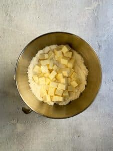 Cubes of butter over flour mixture in mixer bowl.