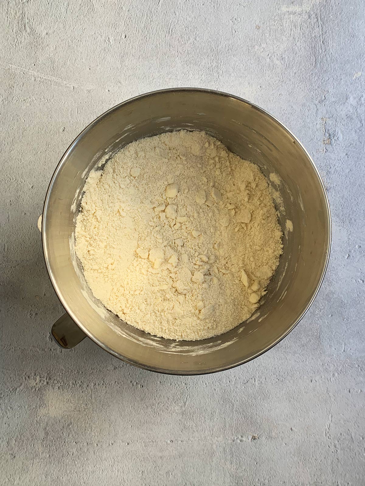 Pie dough in a mixer bowl showing that the butter is being incorporated and pea size pieces are emerging.