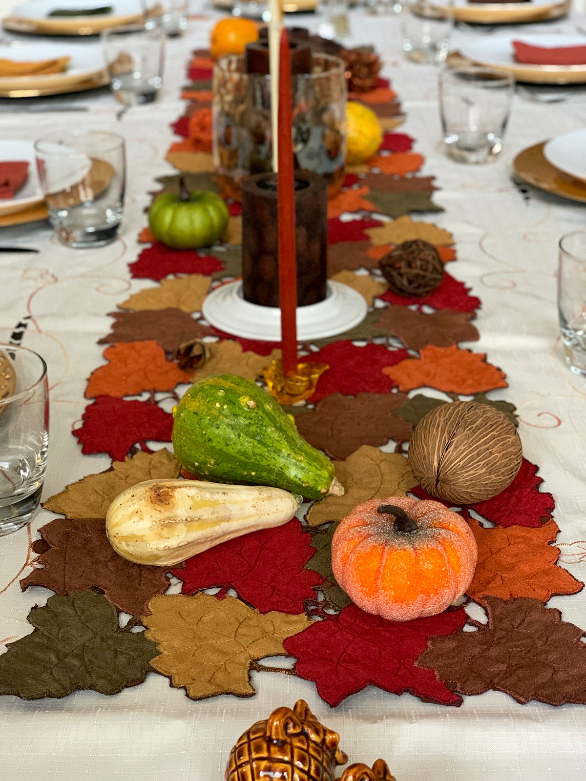 Thanksgiving table setting  with fall colors looking down the middle of the long table.