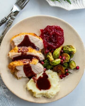 Top down view of a plate of turkey with pomegranate gravy on top.