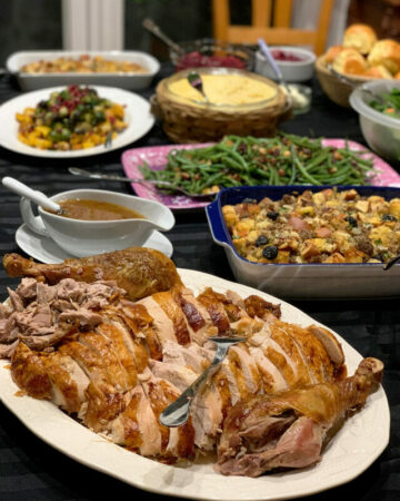 Angle view of a buffet table for Thanksgiving day with a giant platter of turkey in the front.