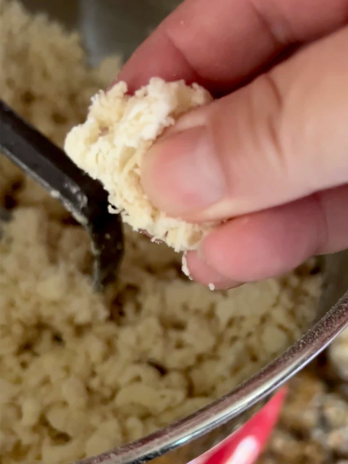 Hand pinching a piece of dough to see if it's ready.