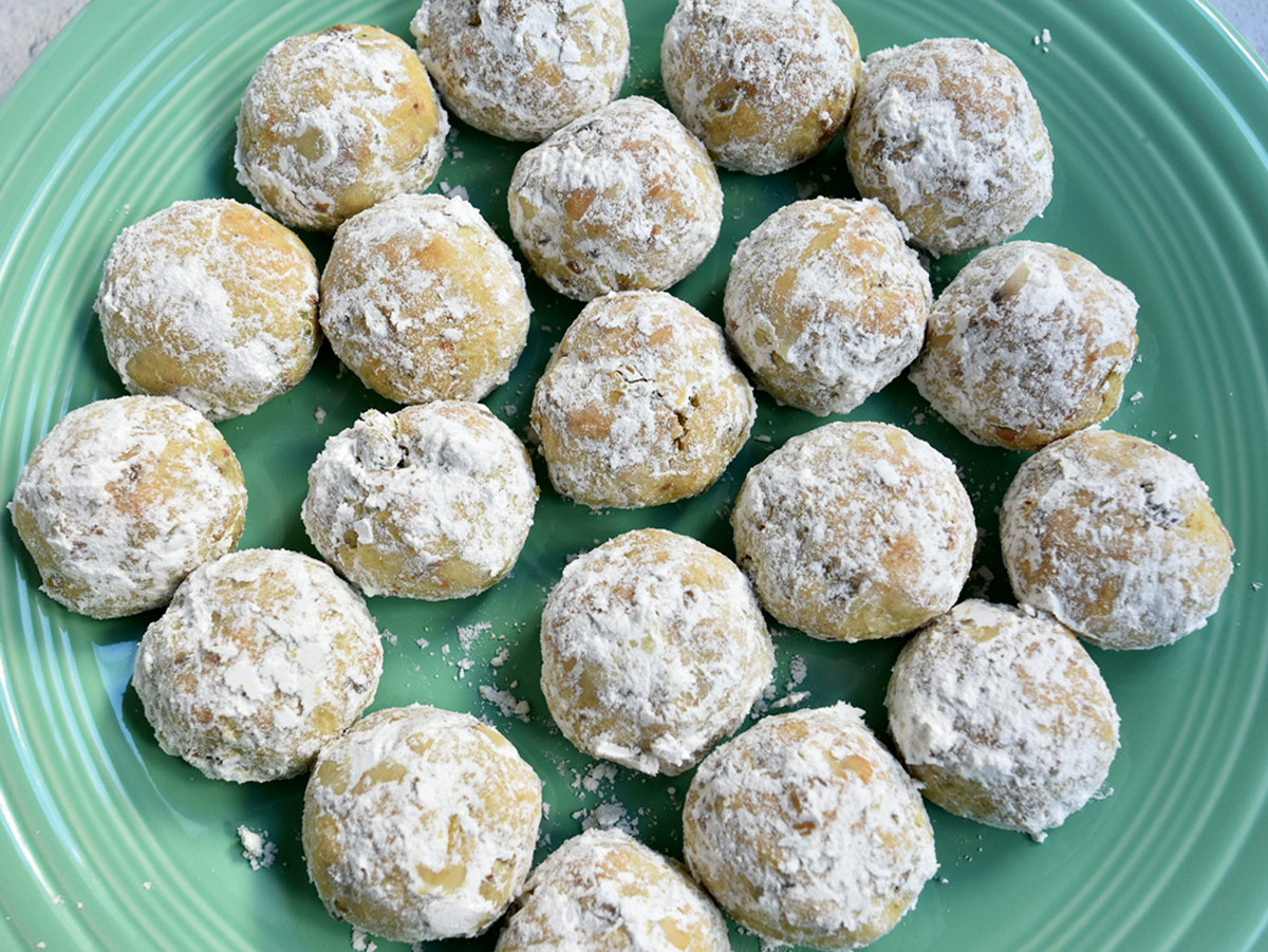 Pistachio snowballs baked with first dusting of powdered sugar on them.