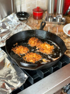Four potato latkes turned over in a frying pan.