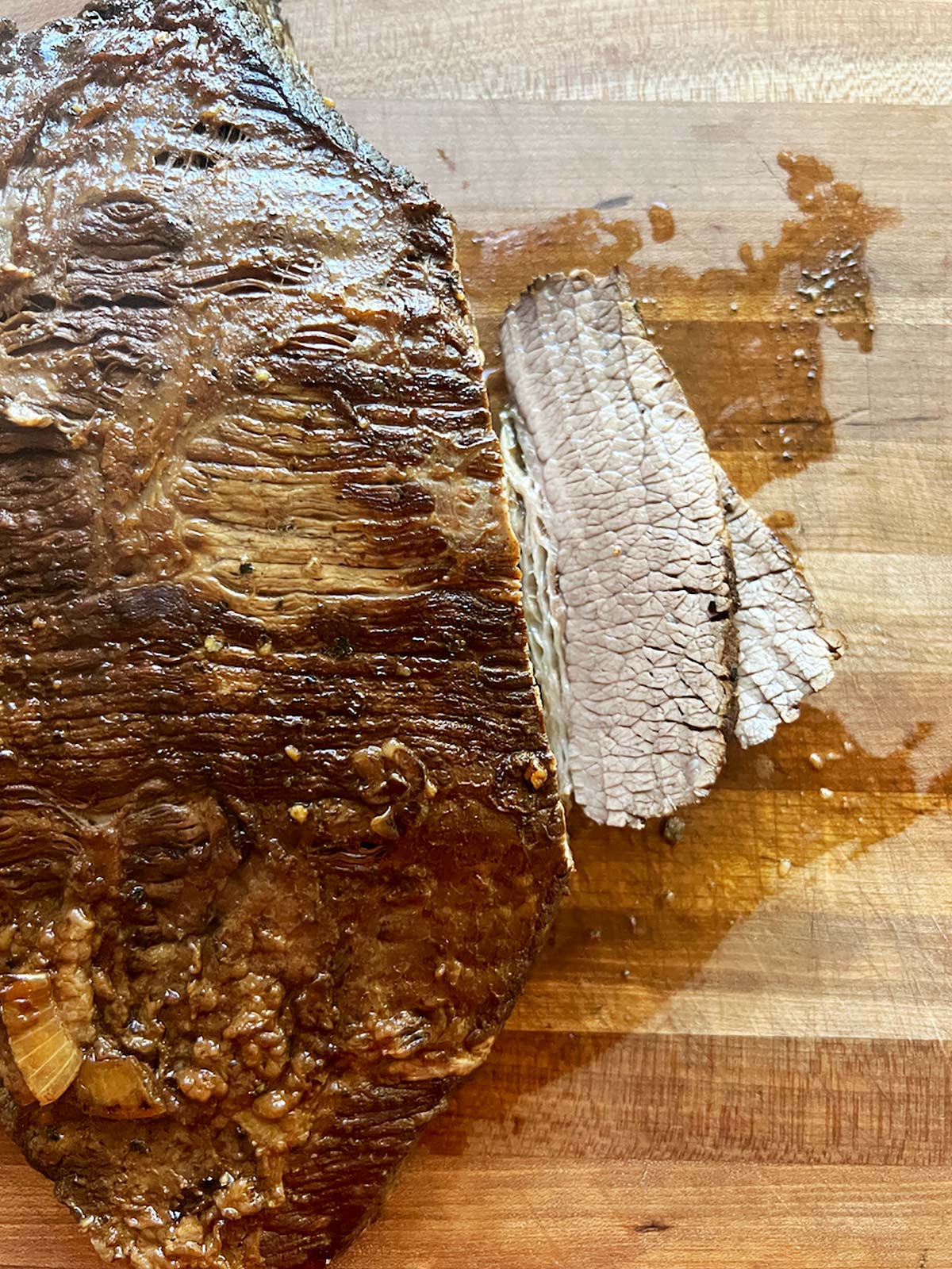 Brisket on a cutting board in the process of being sliced.