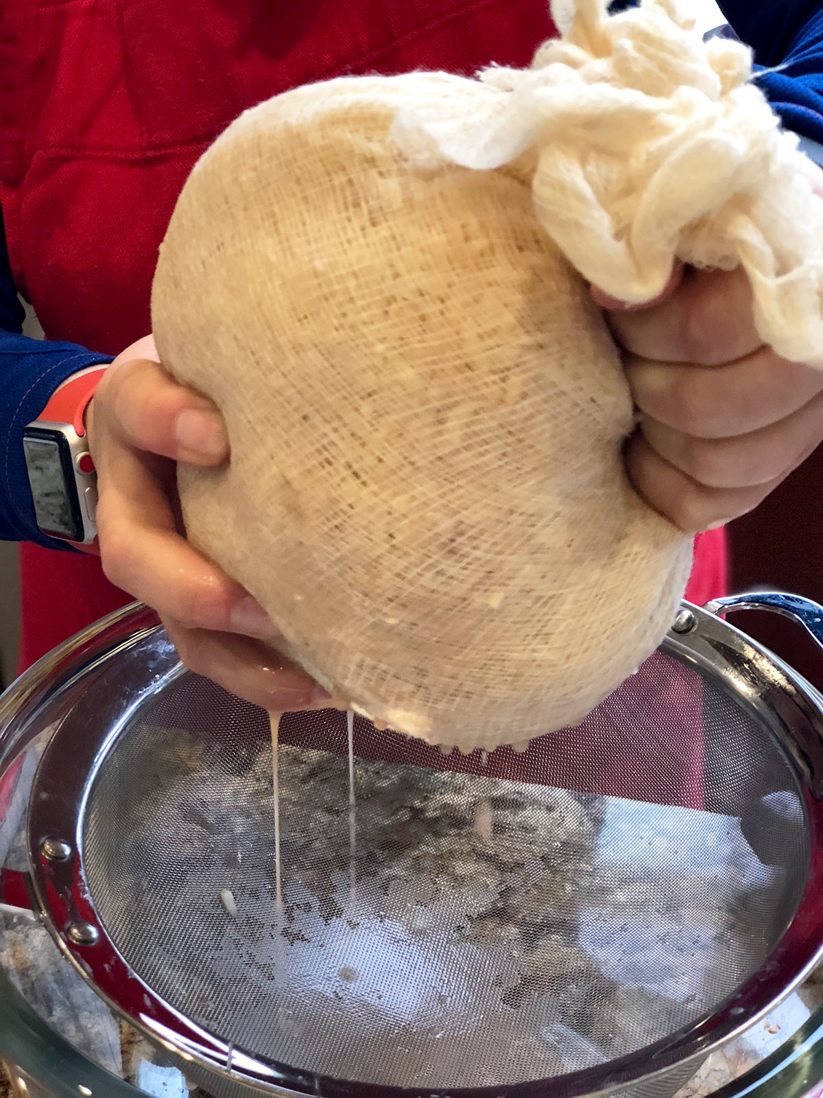 Close up showing potato mixture being wrung out of cheesecloth.