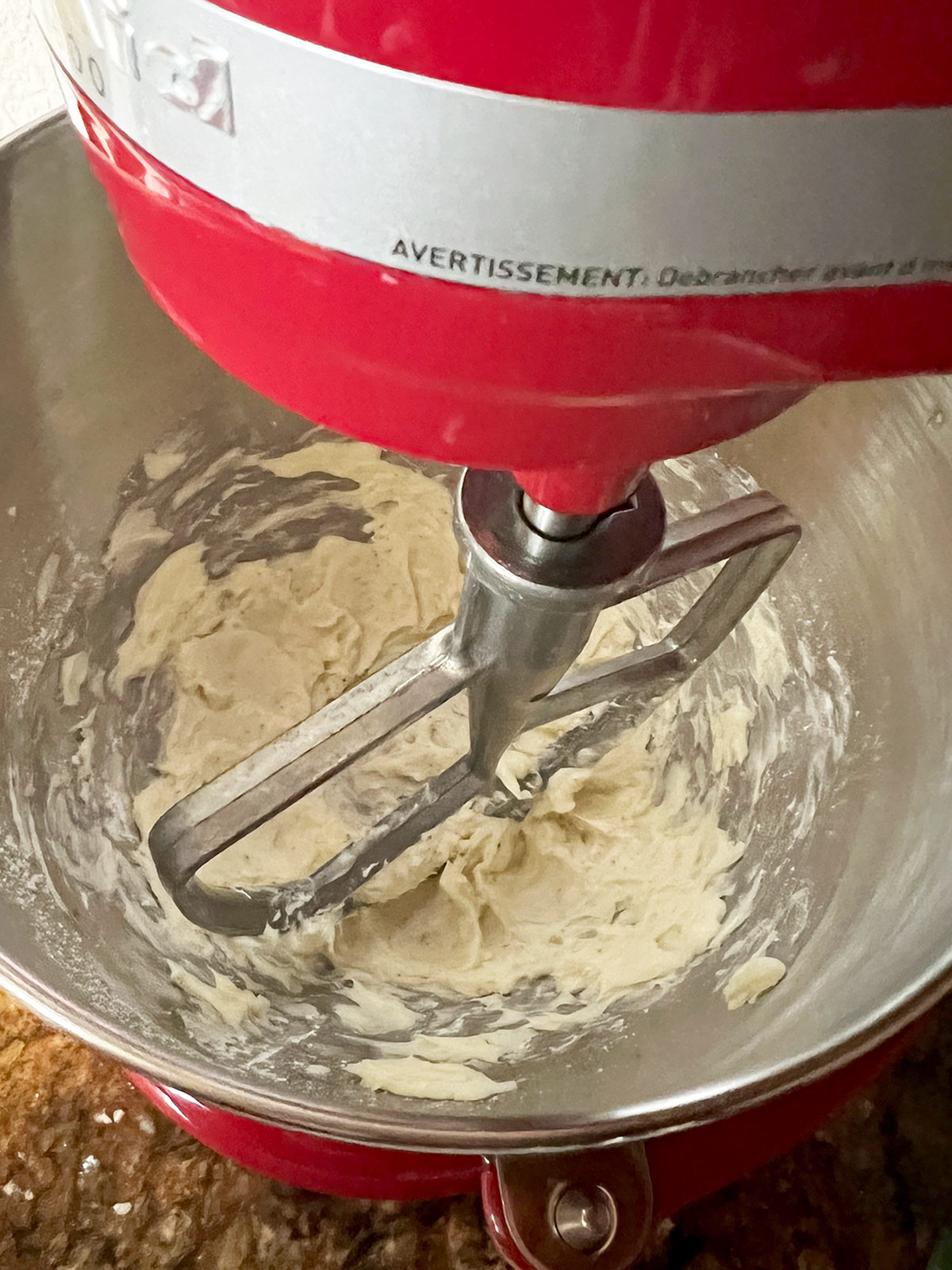 Pistachio snowballs butter creaming in red stand mixer.