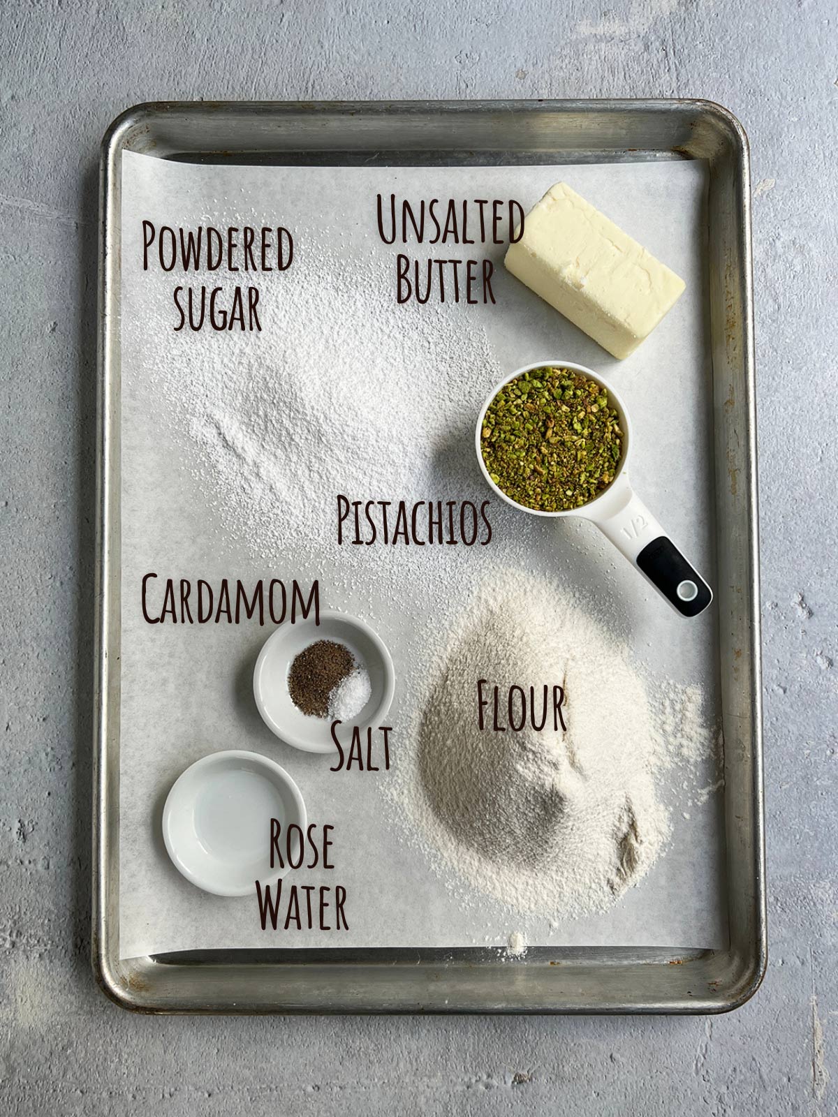 Ingredient shot for pistachio snowballs showing all ingredients on parchment on a baking tray.
