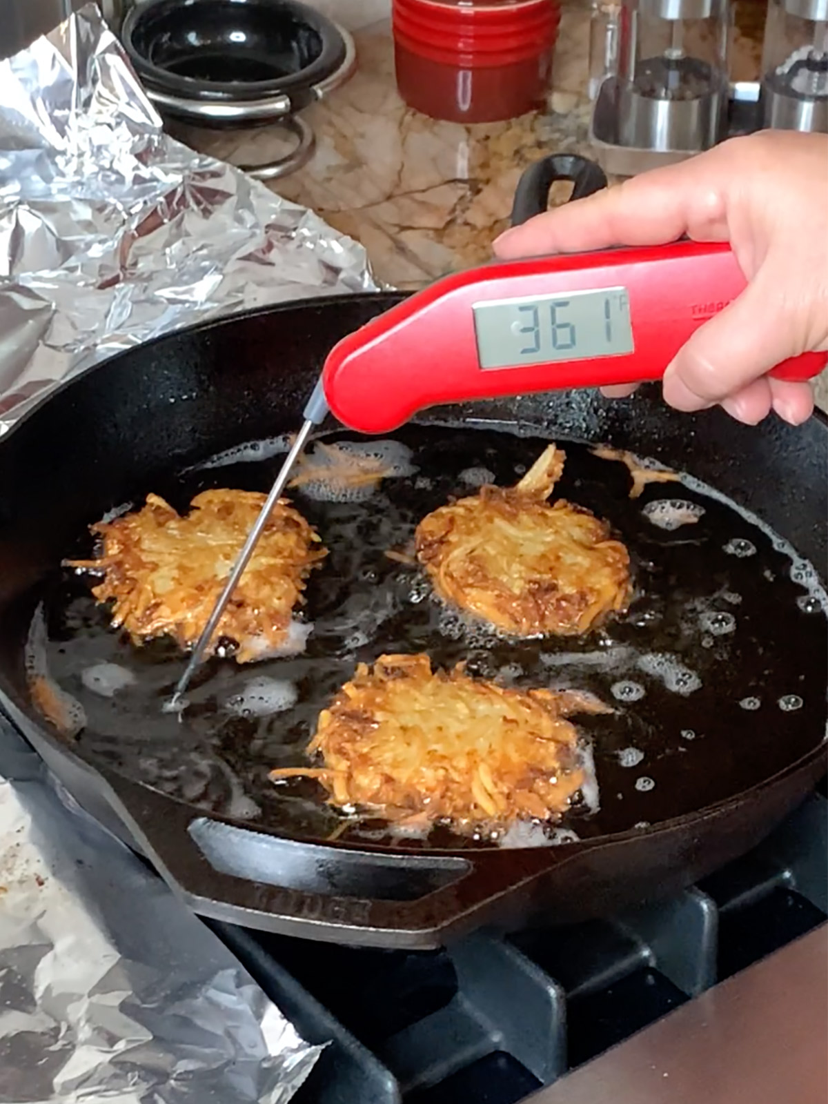 Taking temperature of oil in the frying pan for the crispy latkes.