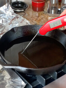 Testing oil temperature in a cast iron pan before adding latkes.