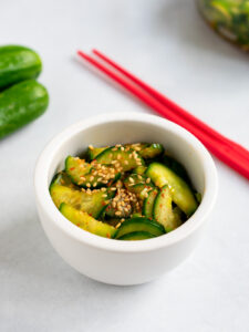 Bowl of Korean cucumber salad with red chopsticks.