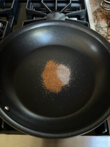 Baharat and cardamom in a large fry pan.