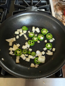 Onions and jalapeno slices in large fry pan.