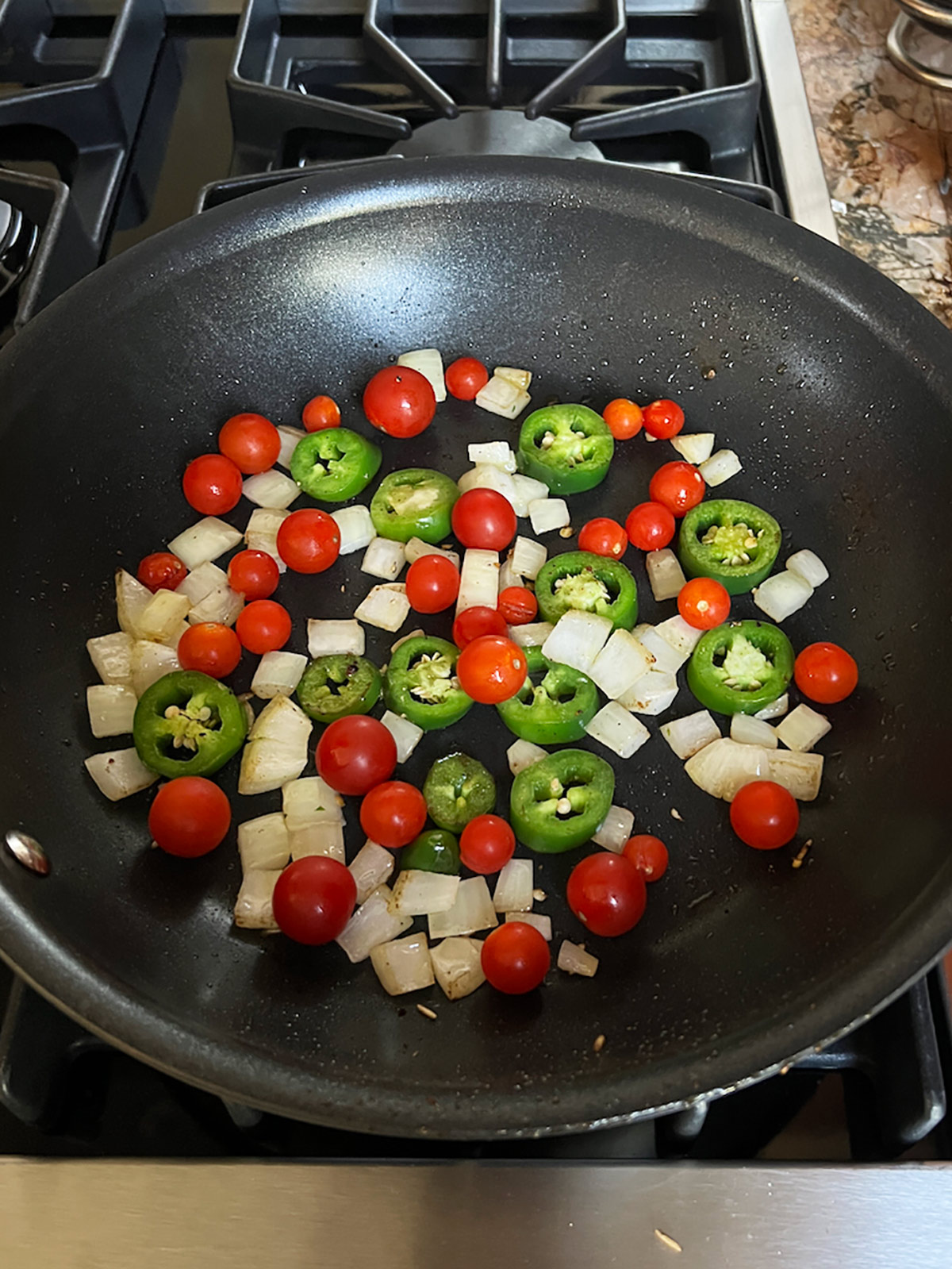 Tomatoes, onions and jalapenos in fry pan ready to place stuffed peppers on top.