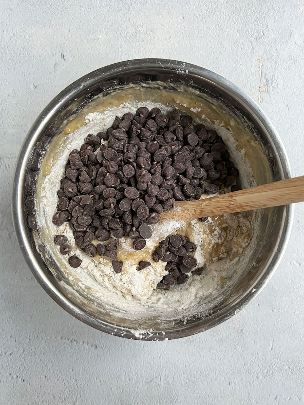 Adding chocolate chips to banana bread batter.