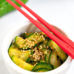Pinterest image showing Korean cucumber salad in a white bowl with red chopsticks.