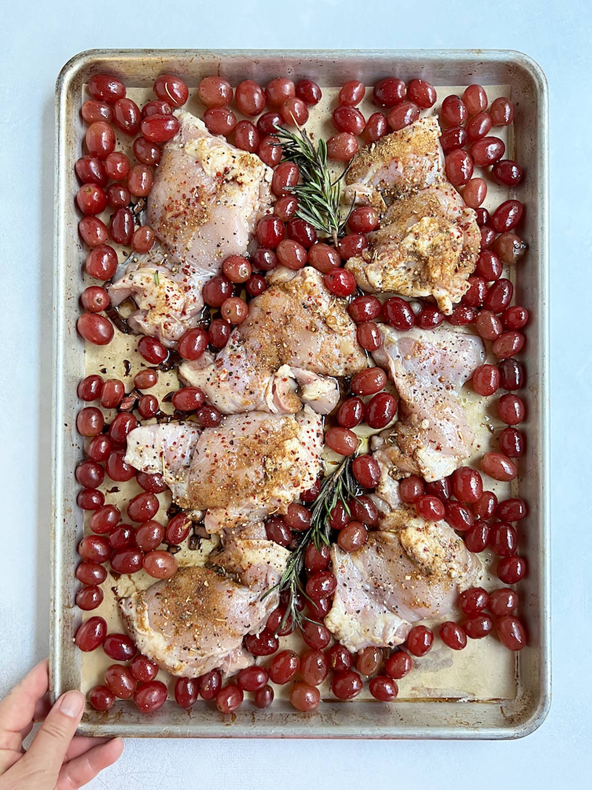 Grapes and chicken on tray uncooked.