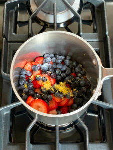 Ingredients for berry compote in a saucepan on the stove.