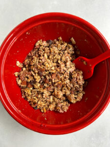 Farfel and egg mixture in a red bowl with red spoonula.