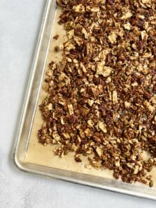 Baked granola on a parchment-lined sheet tray.