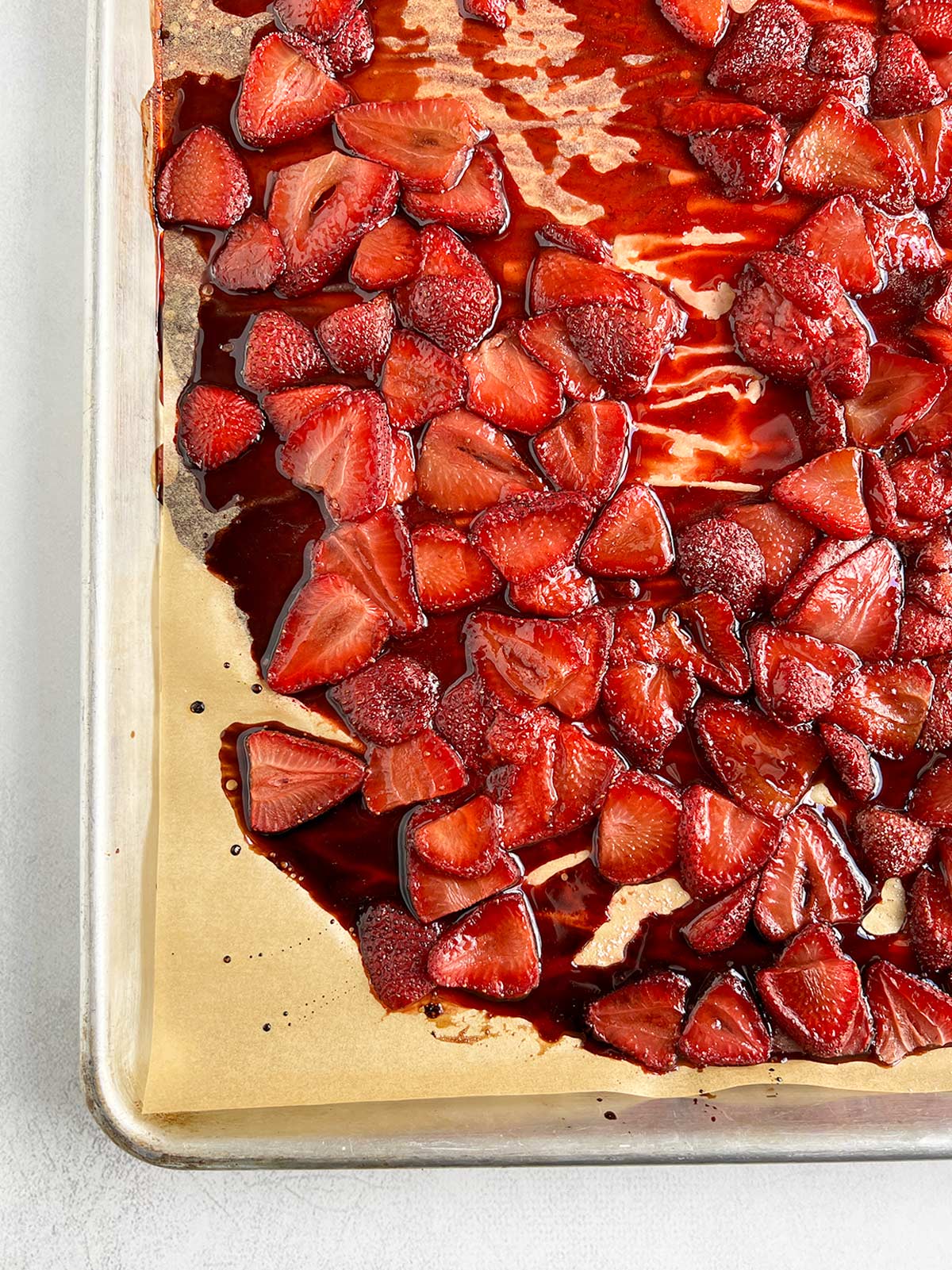 Roasted strawberries on parchment-lined baking sheet.