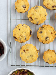 Cranberry orange pistachio sablé cookies baked and on a cooling rack.