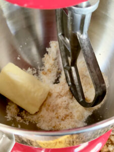 Add stick of butter to orange sugar mixture in stand mixer bowl.