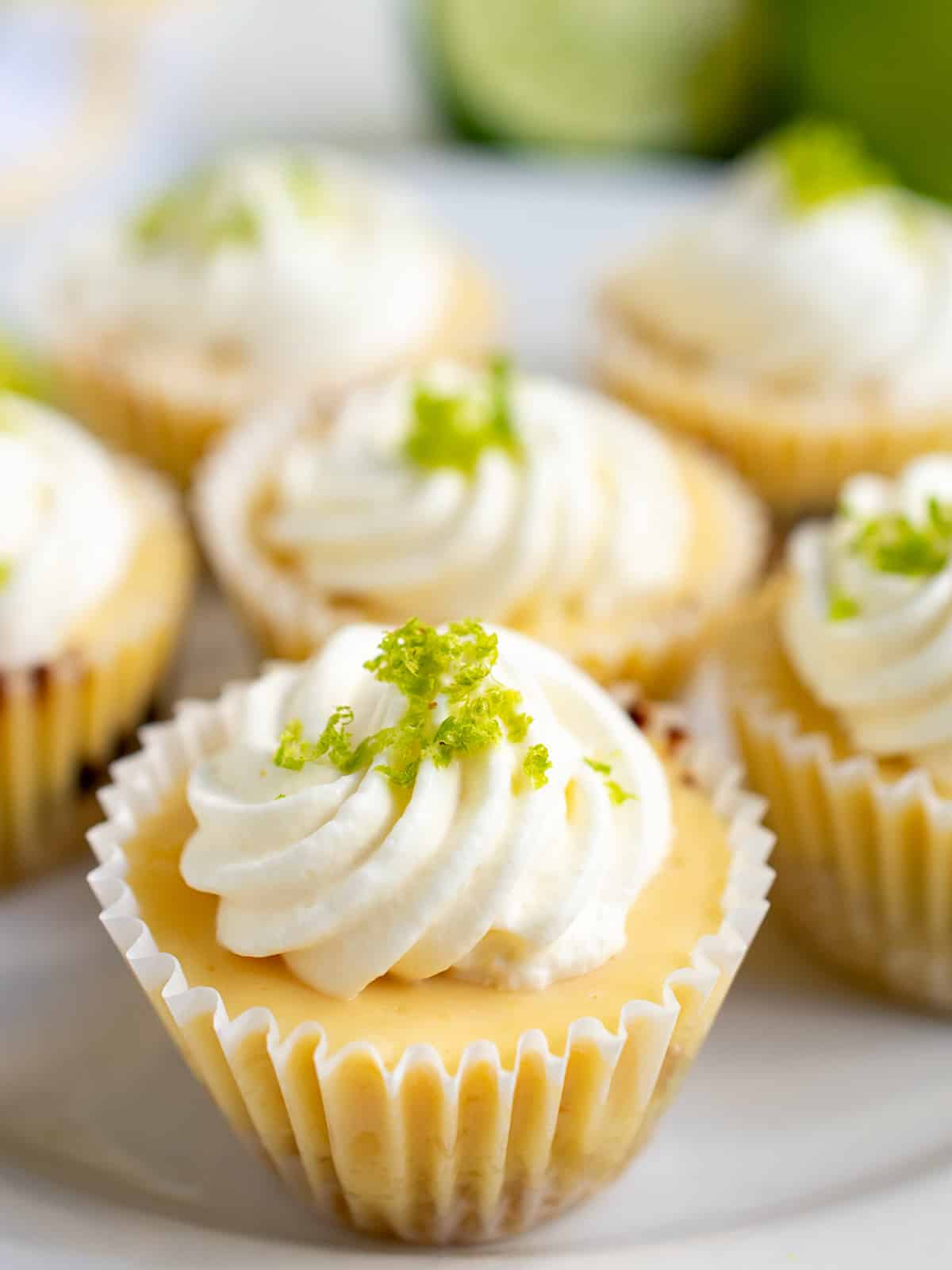 Close up of a mini key lime pie on a white plate filled with several mini pies.