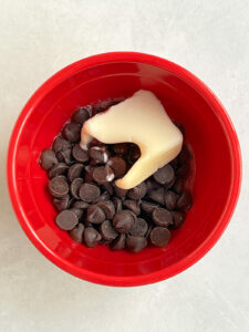 Chocolate and butter in red bowl after first microwave to start the melting.