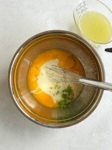 Sweetened condensed milk and lime zest added to egg yolks.